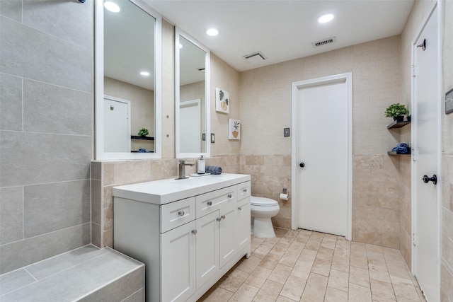 full bath with visible vents, toilet, vanity, tile walls, and recessed lighting