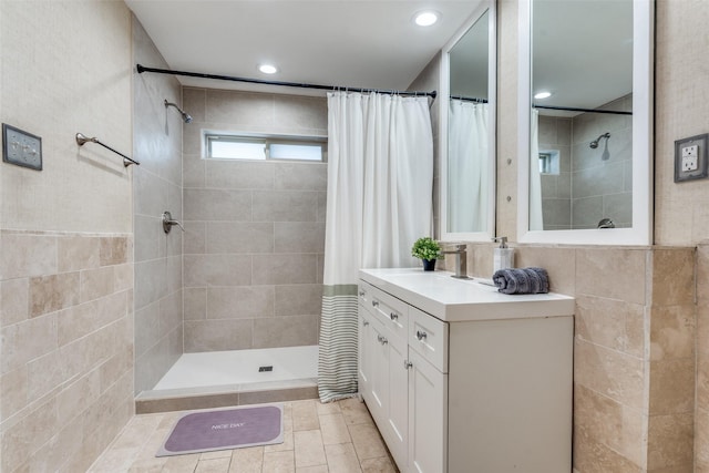 bathroom with tiled shower, recessed lighting, vanity, and tile walls