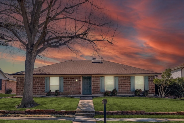 view of front of home featuring brick siding, a front lawn, and roof with shingles