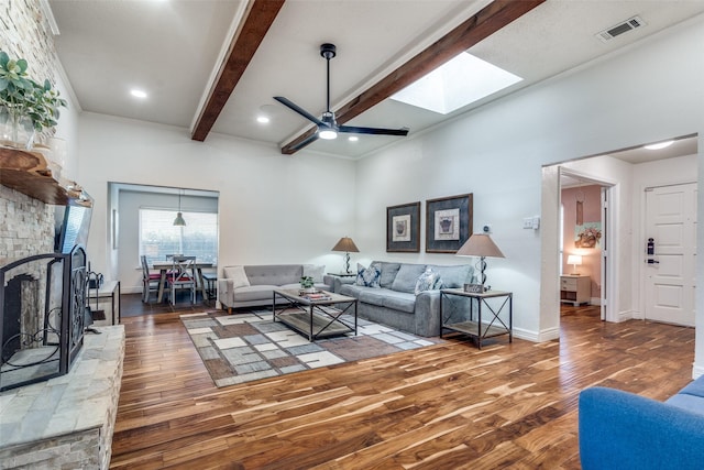 living room featuring a fireplace, a skylight, wood finished floors, visible vents, and beamed ceiling