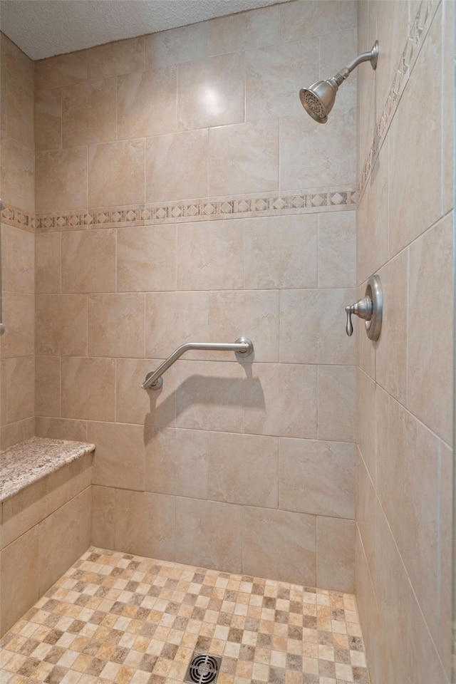 full bath with tiled shower and a textured ceiling