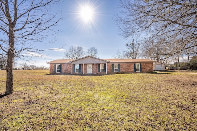 ranch-style home with a garage, a front yard, an outdoor structure, and brick siding