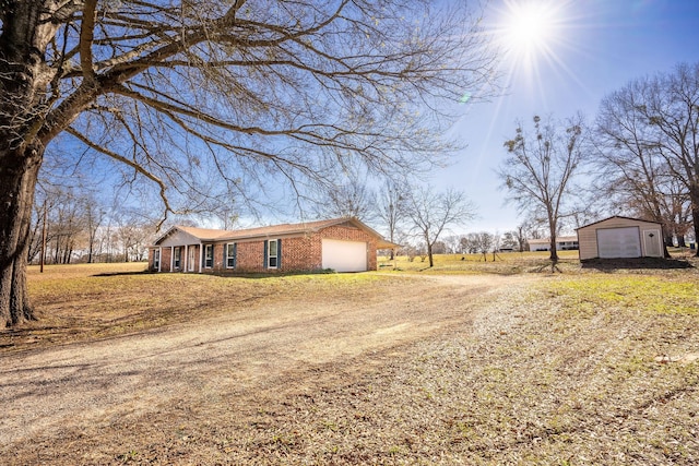 exterior space with a garage, brick siding, and dirt driveway