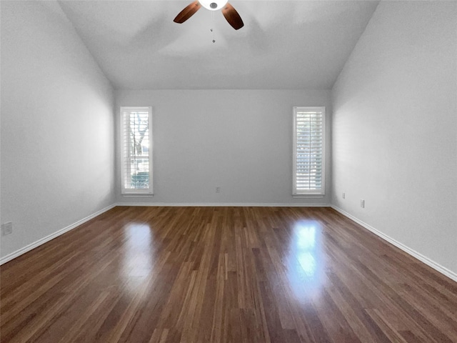 empty room featuring baseboards, vaulted ceiling, and dark wood-type flooring