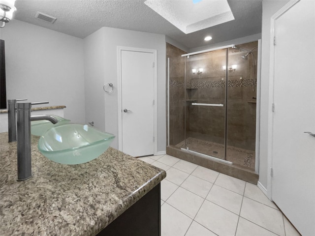 full bathroom with visible vents, a textured ceiling, vanity, a shower stall, and tile patterned floors