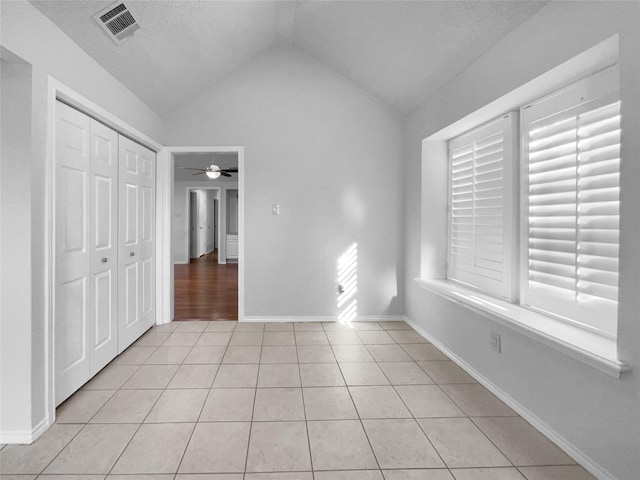 unfurnished bedroom with light tile patterned floors, a closet, visible vents, vaulted ceiling, and baseboards