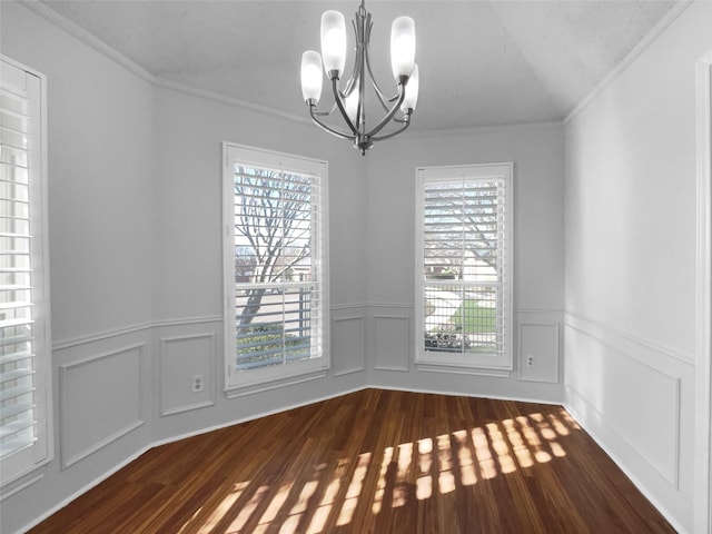 unfurnished dining area featuring ornamental molding, dark wood-style flooring, wainscoting, and a notable chandelier