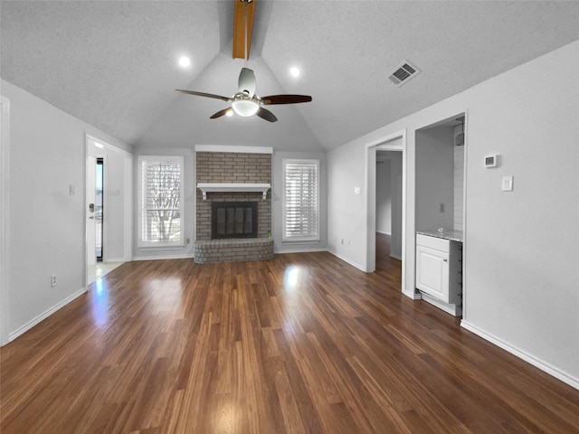 unfurnished living room featuring a wealth of natural light, a fireplace, wood finished floors, and visible vents