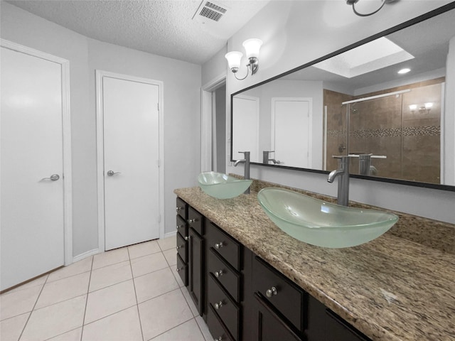 full bath with a stall shower, tile patterned flooring, visible vents, and a sink