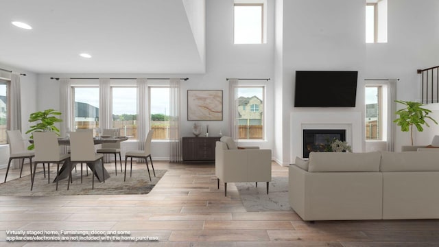 4343 Hudson St, Fate, TX 75087 - living room with wood finished floors, healthy amount of natural light, recessed lighting, a towering ceiling, and a glass covered fireplace