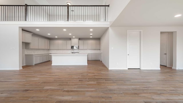 4343 Hudson St, Fate, TX 75087 - kitchen featuring stainless steel microwave, backsplash, light wood finished floors, recessed lighting, and a towering ceiling