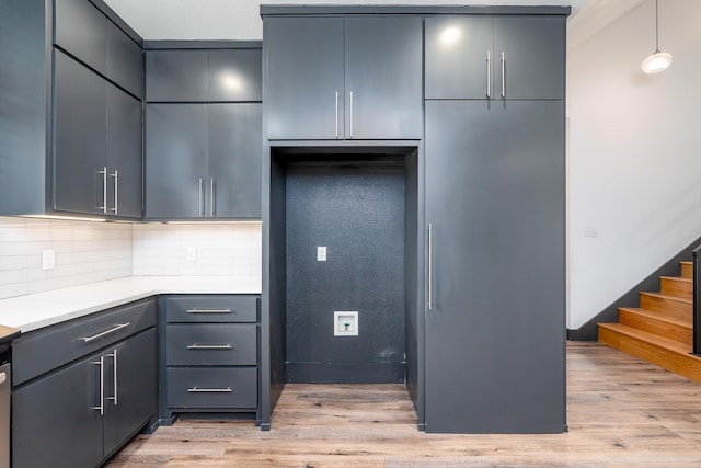 kitchen with gray cabinetry, light wood-style floors, light countertops, backsplash, and pendant lighting