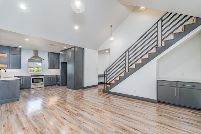 kitchen with light wood-style floors, a sink, wall chimney range hood, and stainless steel electric range