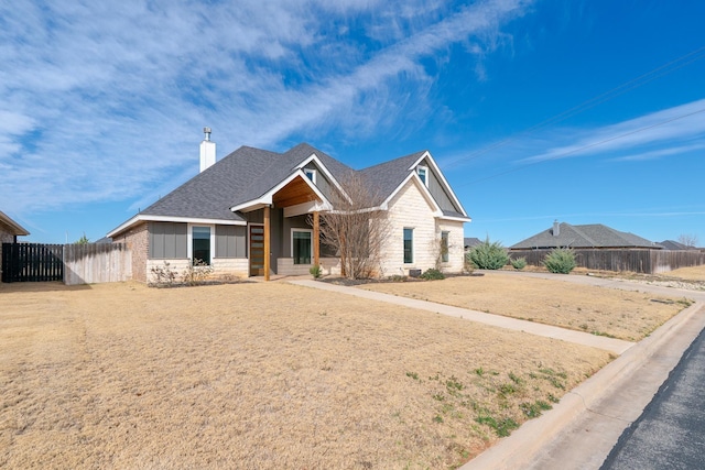 view of front of property with a shingled roof, a chimney, and fence