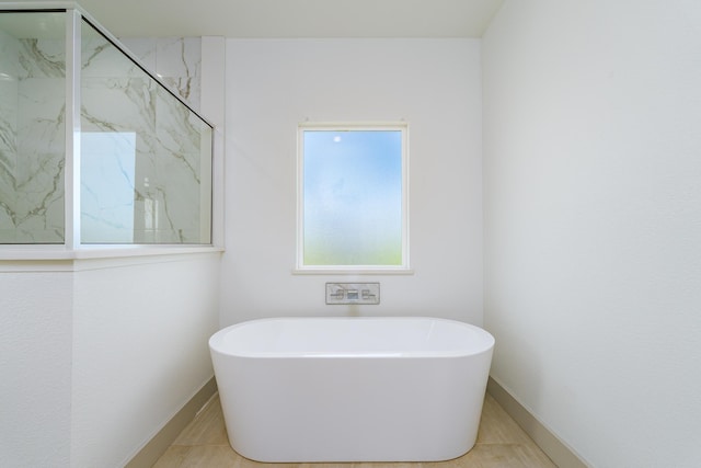 full bathroom with baseboards, a freestanding bath, and a marble finish shower