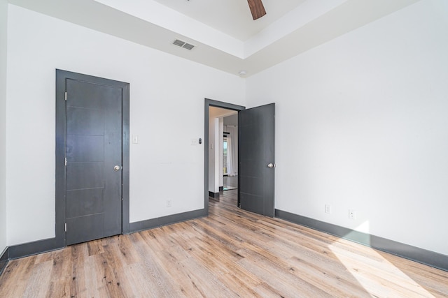 unfurnished bedroom featuring ceiling fan, wood finished floors, visible vents, and baseboards