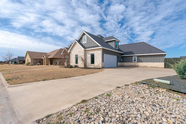 view of front of house with driveway, stone siding, fence, and board and batten siding