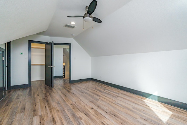 additional living space featuring lofted ceiling, visible vents, baseboards, and wood finished floors