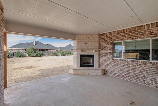 view of patio with a large fireplace and fence