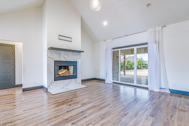 unfurnished living room featuring high vaulted ceiling, wood finished floors, baseboards, and a premium fireplace