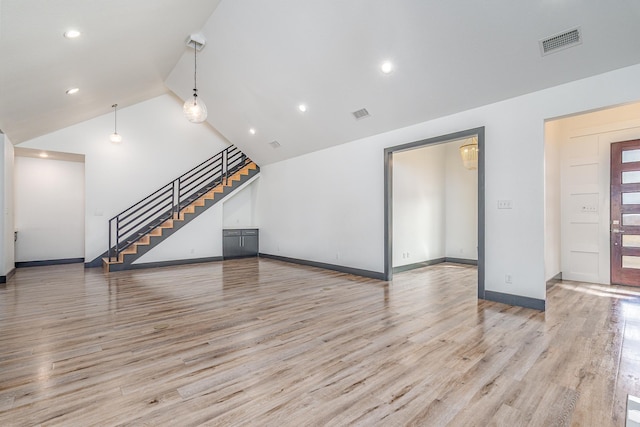 unfurnished living room featuring baseboards, visible vents, stairs, vaulted ceiling, and light wood-type flooring