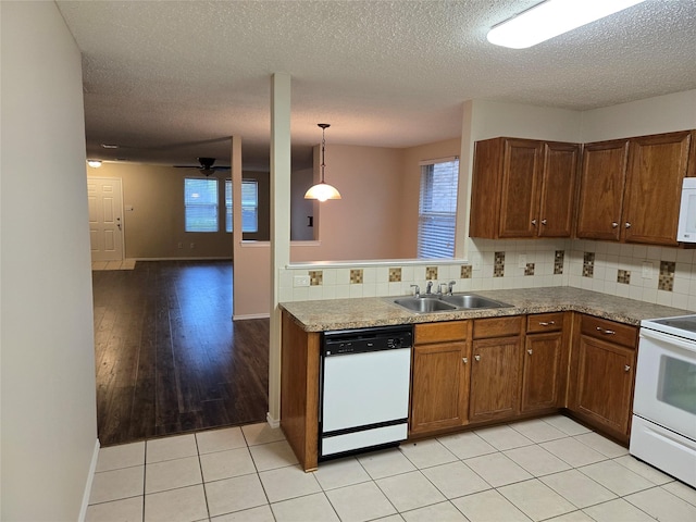 kitchen with white appliances, backsplash, a sink, and brown cabinetry