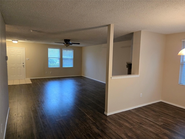 spare room with baseboards, dark wood-type flooring, visible vents, and a ceiling fan