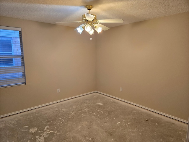 empty room with a textured ceiling, unfinished concrete flooring, a ceiling fan, and baseboards