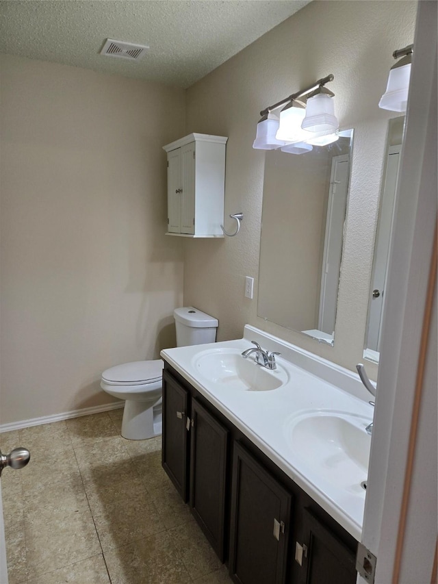 bathroom with toilet, a textured ceiling, visible vents, and a sink