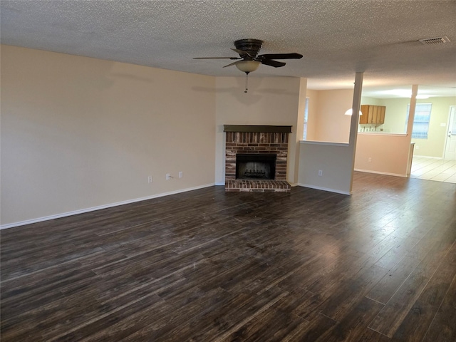 unfurnished living room featuring dark wood-type flooring, visible vents, a fireplace, and baseboards