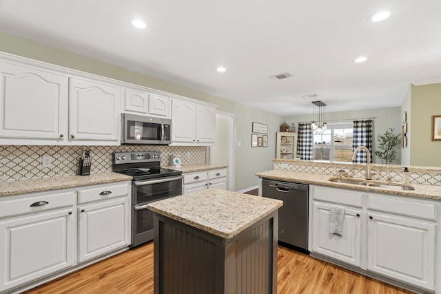 kitchen featuring visible vents, white cabinets, stainless steel appliances, light wood-style floors, and a sink