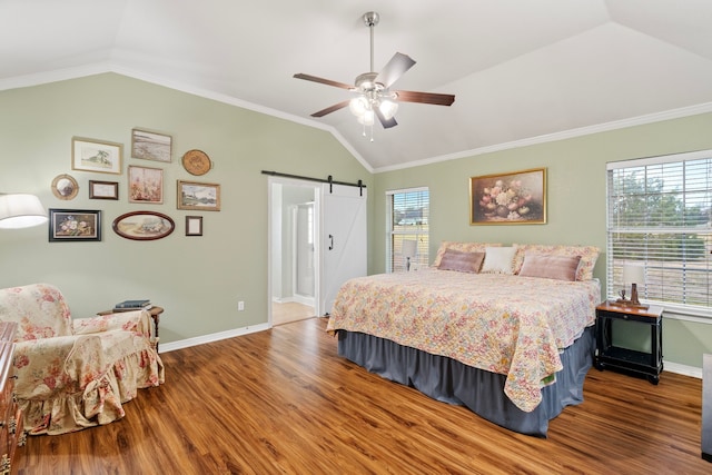 bedroom with a barn door, baseboards, ornamental molding, wood finished floors, and vaulted ceiling