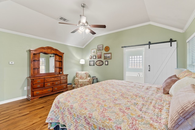 bedroom featuring a barn door, visible vents, lofted ceiling, wood finished floors, and crown molding