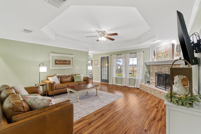 living area featuring a tray ceiling, visible vents, and a fireplace