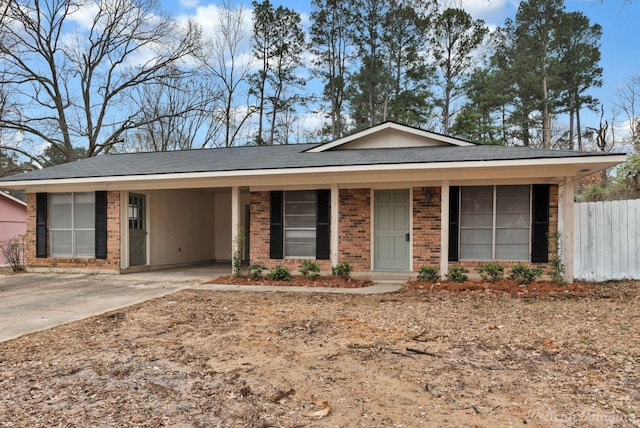 ranch-style house with a carport, concrete driveway, brick siding, and fence