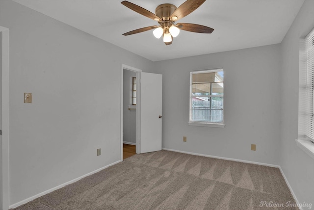 carpeted spare room with ceiling fan and baseboards