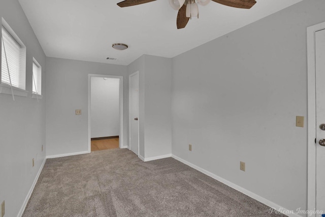 unfurnished room featuring carpet flooring, ceiling fan, visible vents, and baseboards