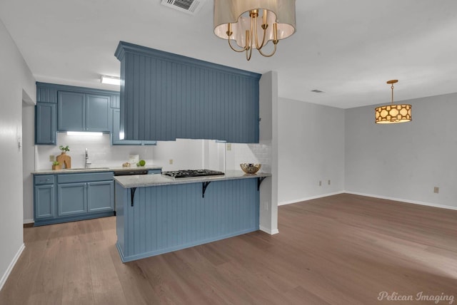 kitchen featuring a peninsula, wood finished floors, and blue cabinets