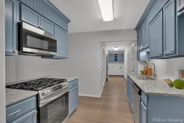 kitchen featuring blue cabinets, stainless steel appliances, backsplash, and wood finished floors