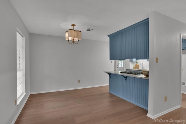 kitchen with blue cabinetry, wood finished floors, and a kitchen breakfast bar