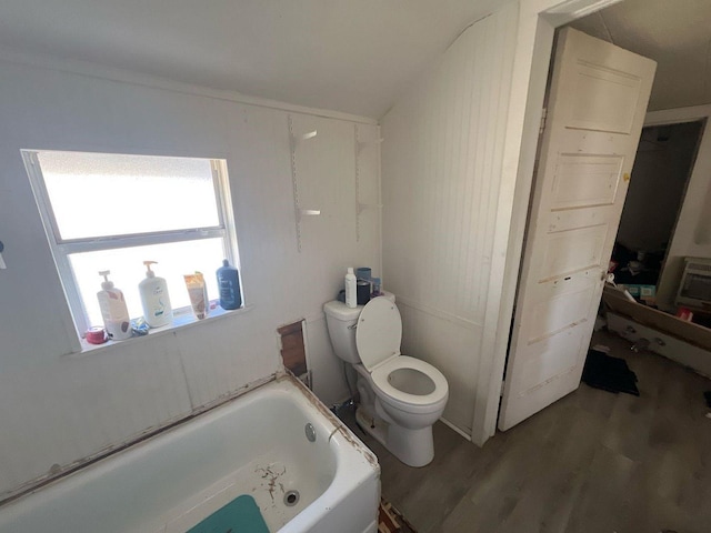 full bath with wood finished floors, toilet, and a tub