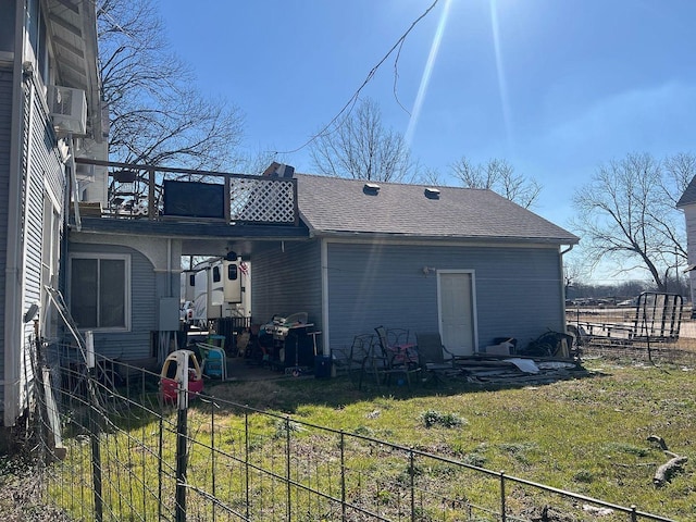 back of property with fence, a lawn, and roof with shingles