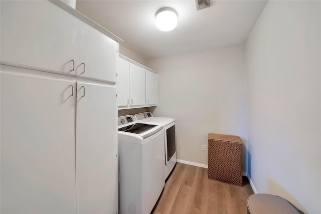 laundry room featuring cabinet space, visible vents, baseboards, washing machine and clothes dryer, and light wood-type flooring