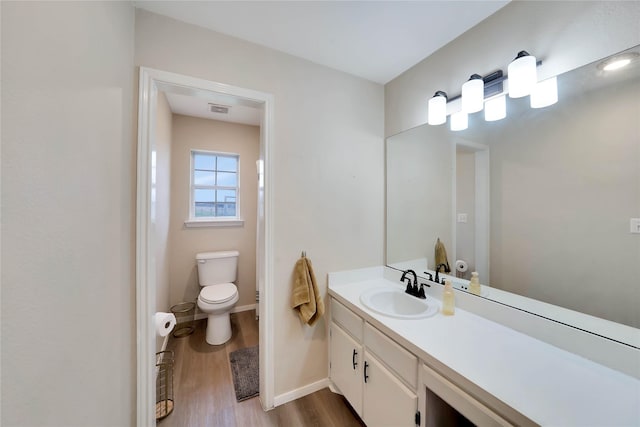 bathroom with visible vents, baseboards, toilet, wood finished floors, and vanity