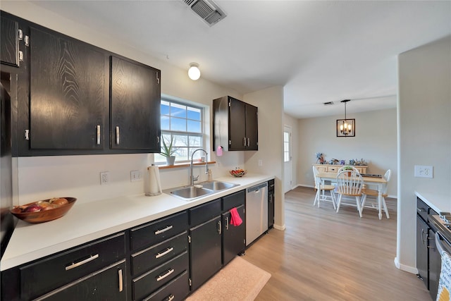 kitchen featuring dishwasher, light countertops, a sink, and light wood-style flooring