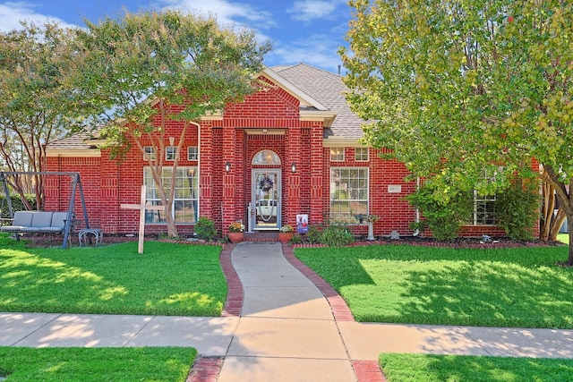 view of front facade with roof with shingles, a front lawn, and brick siding