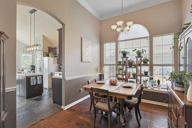 dining room with baseboards, arched walkways, dark wood finished floors, crown molding, and a chandelier