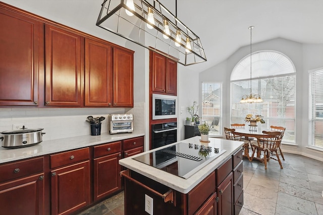 kitchen with black appliances, a chandelier, decorative backsplash, and stone tile flooring