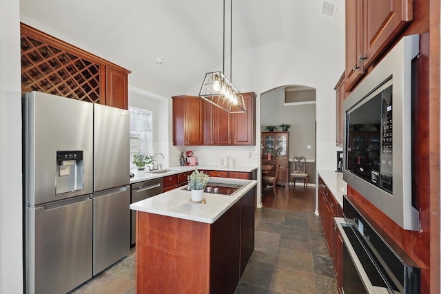 kitchen with visible vents, a kitchen island, decorative light fixtures, stainless steel appliances, and light countertops