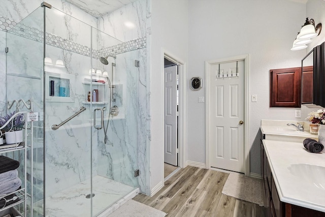 bathroom with a sink, double vanity, a marble finish shower, and wood finished floors